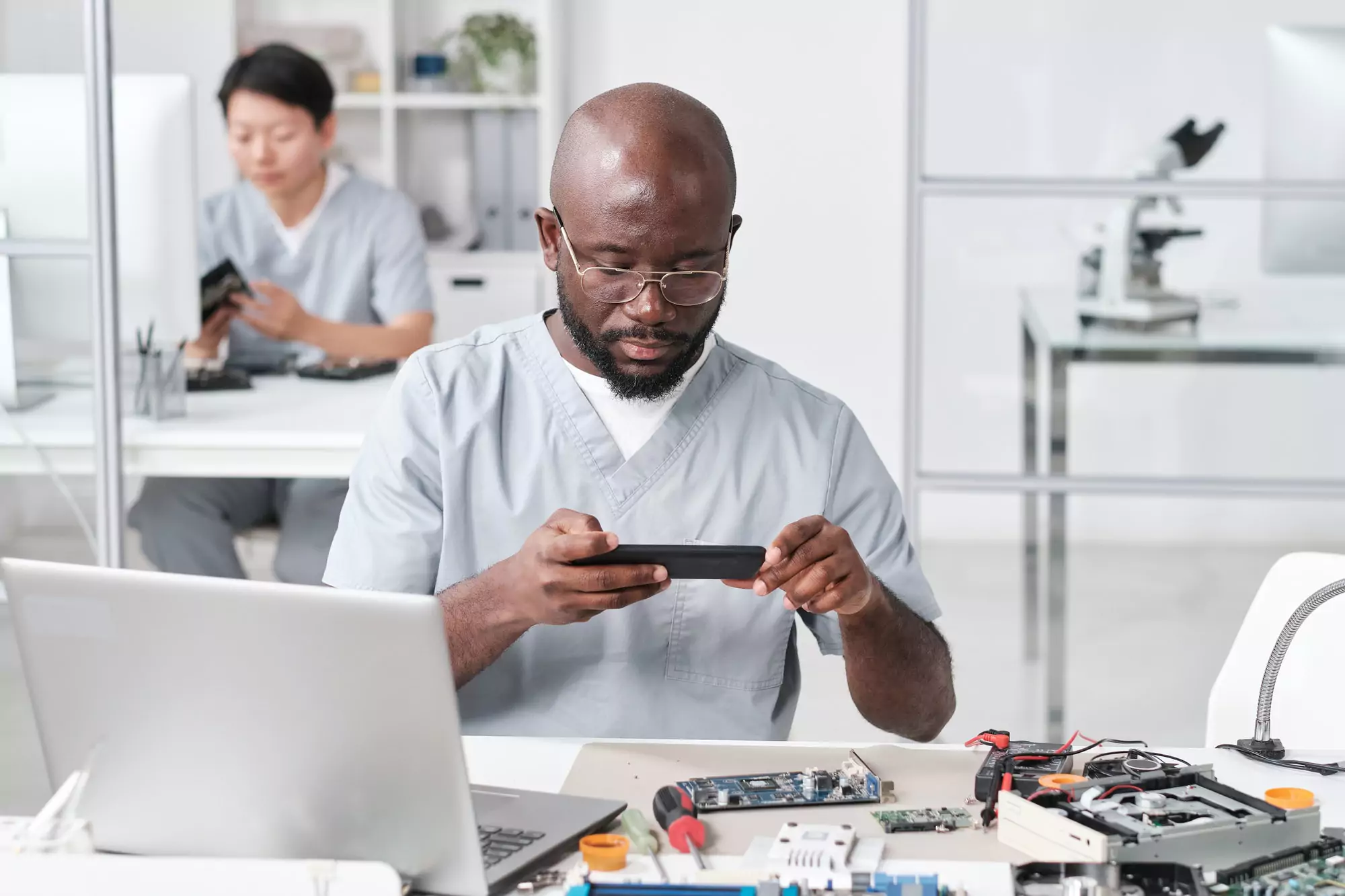 African repairman with smartphone photographing circuit board
