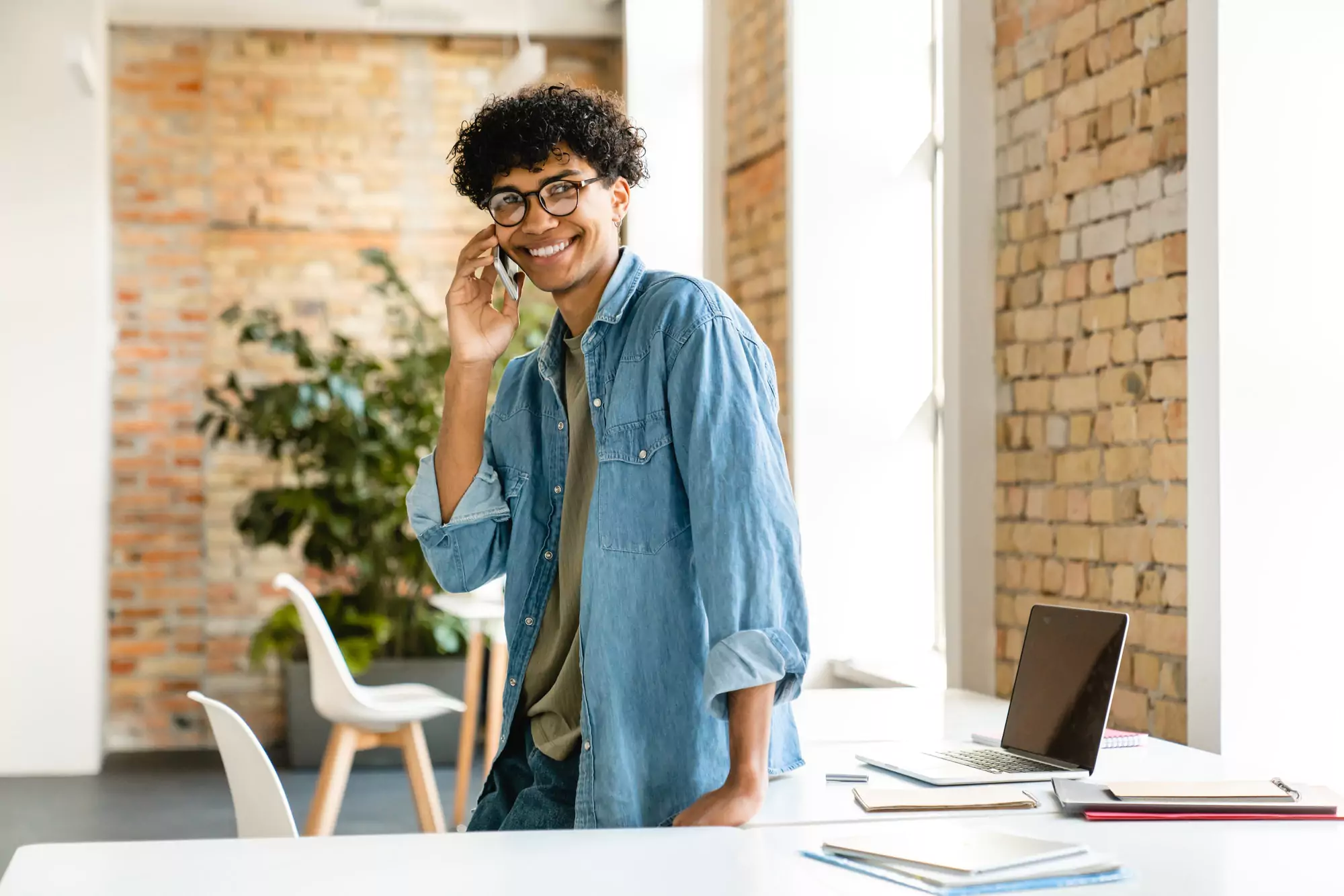 Cheerful young african businessman talking on phone in the office