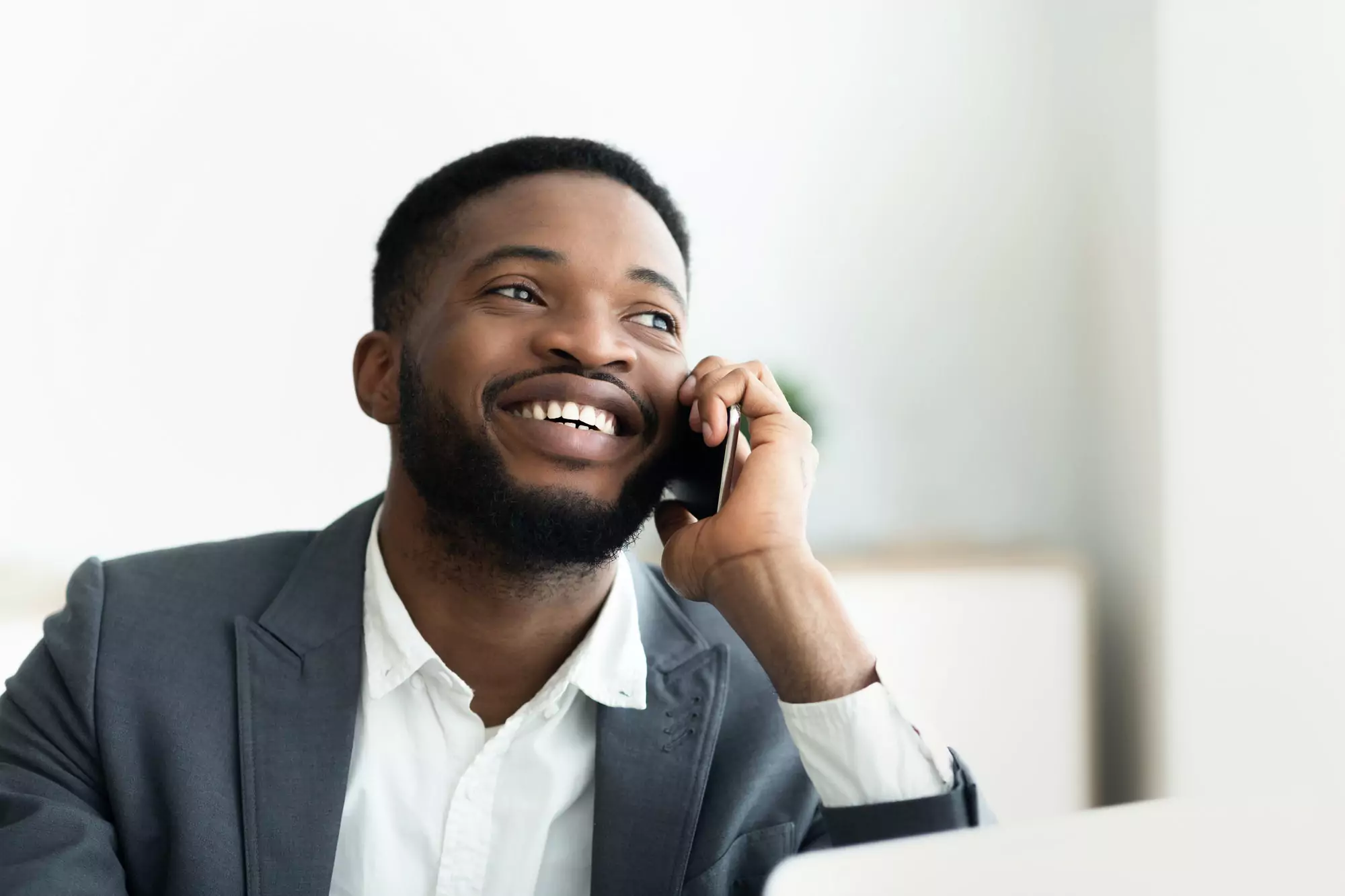 Glad african businessman talking on cellphone at office