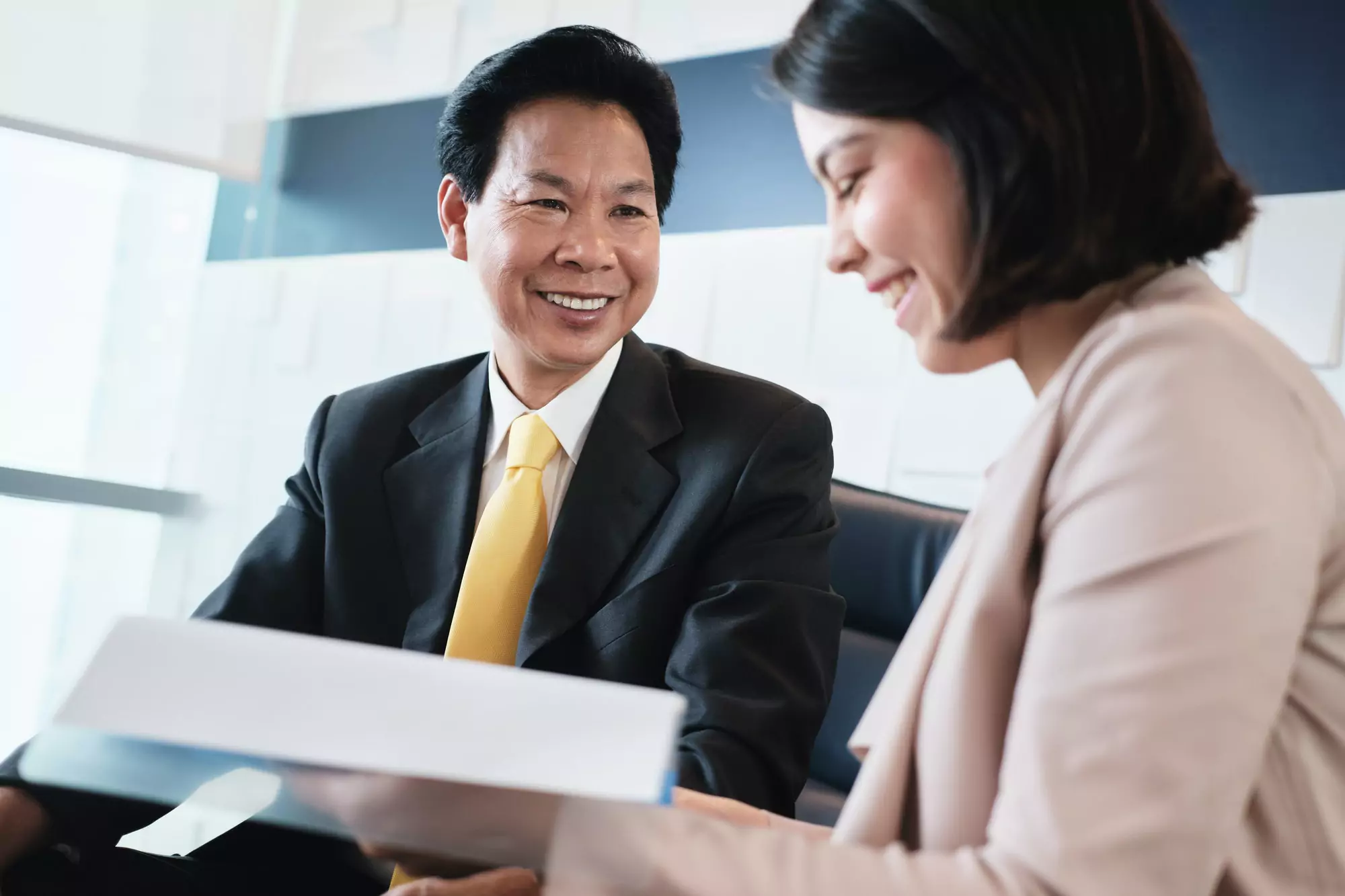 Investment Plan Agent Showing Documents To Asian Customer In Bank