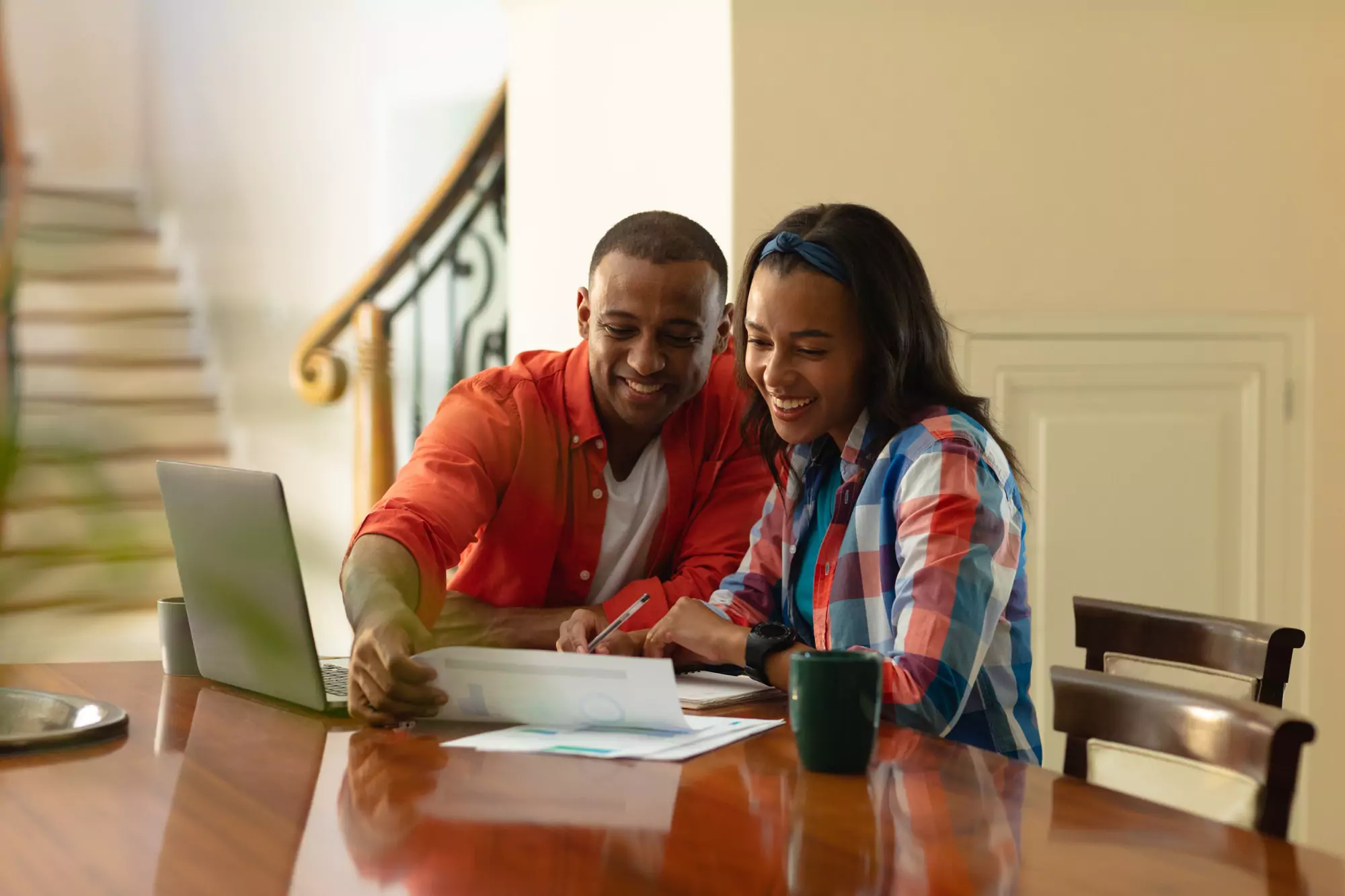 Smiling african american couple discussing on financial bills while sitting with laptop at home