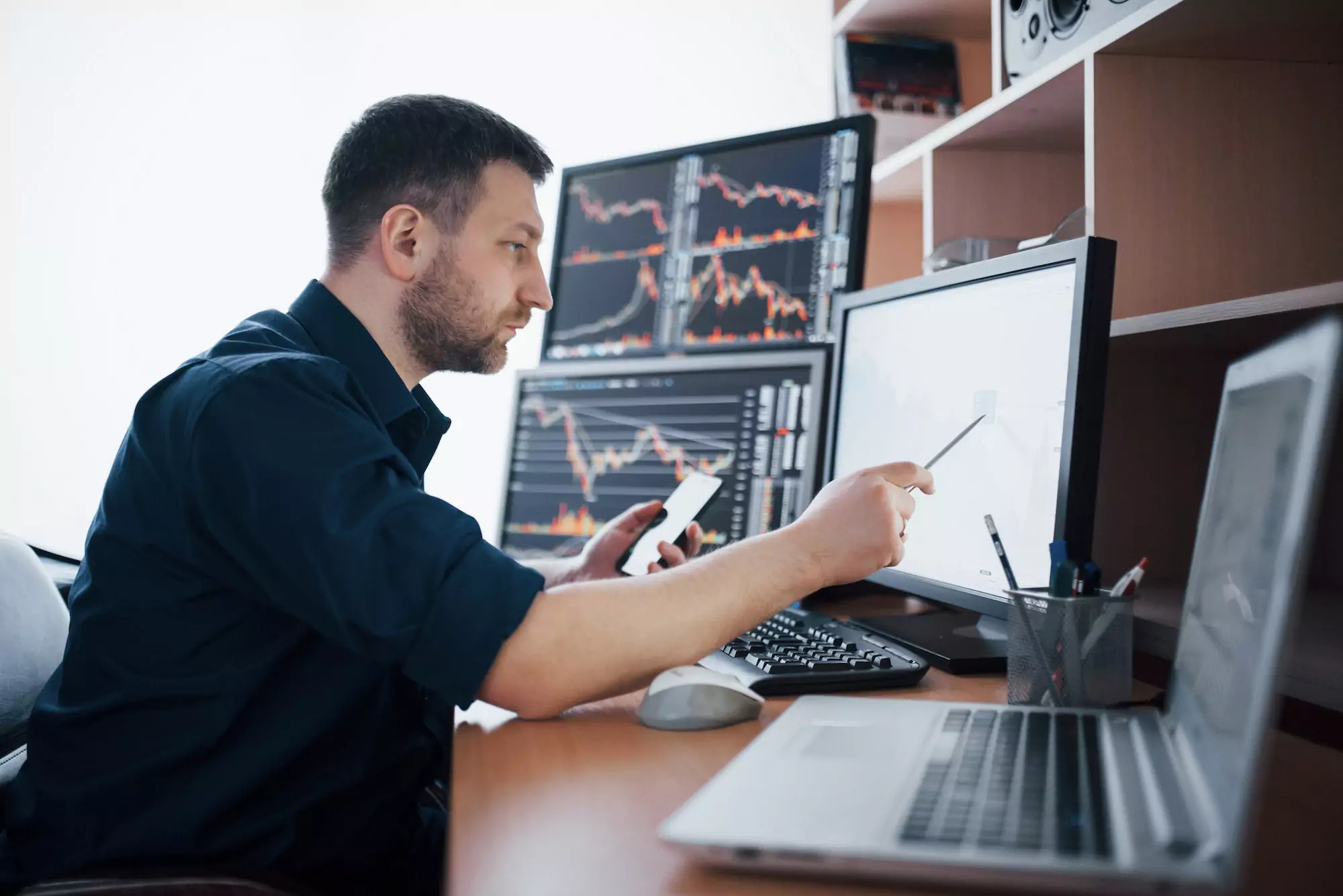 Stockbroker in shirt is working in a monitoring room with display screens. Stock Exchange Trading